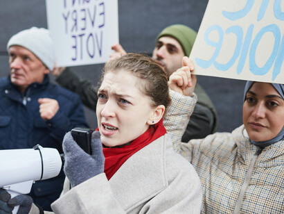 With a megaphone in hand, a woman speaks out at a protest, symbolizing the strength of free expression and open public debate
