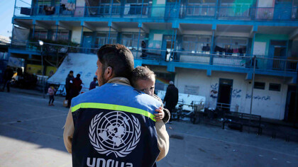 UNRWA staff member comforts a distressed child at a school shelter in Nuseirat camp, Gaza Strip, Palestine