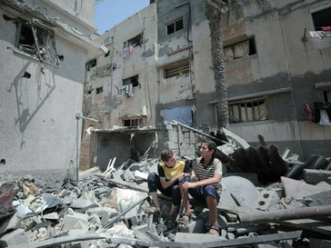 Children near a collapsed building in Gaza, reflecting the devastation from residential bombings and the severe humanitarian crisis