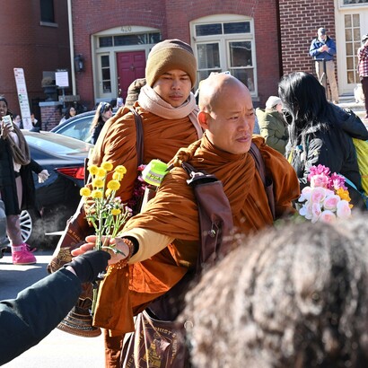 Un monaco buddista prende dei fiori dalla mano di uno spettatore lungo la strada durante la Marcia per la Pace. Foto di G. Edward Johnson
