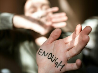 A man holding out his palm with "enough" scribbled on it, highlighting how lack of validation at a young age can lead to a lifelong quest for approval and acceptance