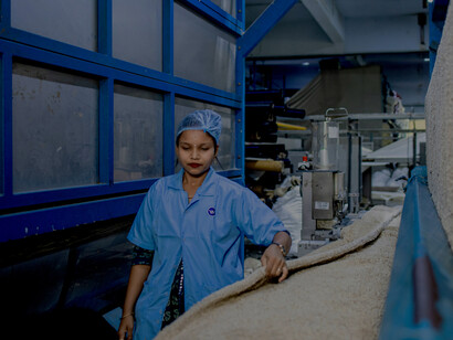 A smiling factory worker confidently operates a textile machine, reflecting skill, focus, and pride in modern manufacturing