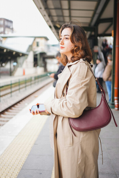 A woman stands alone on a train station platform, anticipating her next journey