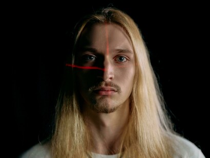 Portrait of a man with laser lines on his face, depicting biometric surveillance and facial recognition systems