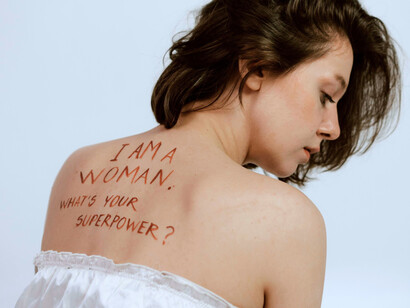 A woman marked with a bold message, representing the silent force of unpaid and undervalued labour women perform