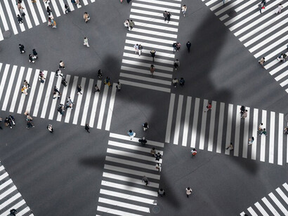 People in silhouette pausing at a busy city crossroads