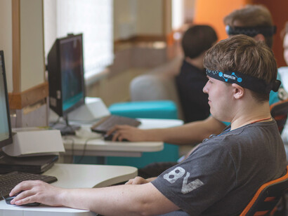 Classroom scene with students testing electronic headbands for brainwave monitoring