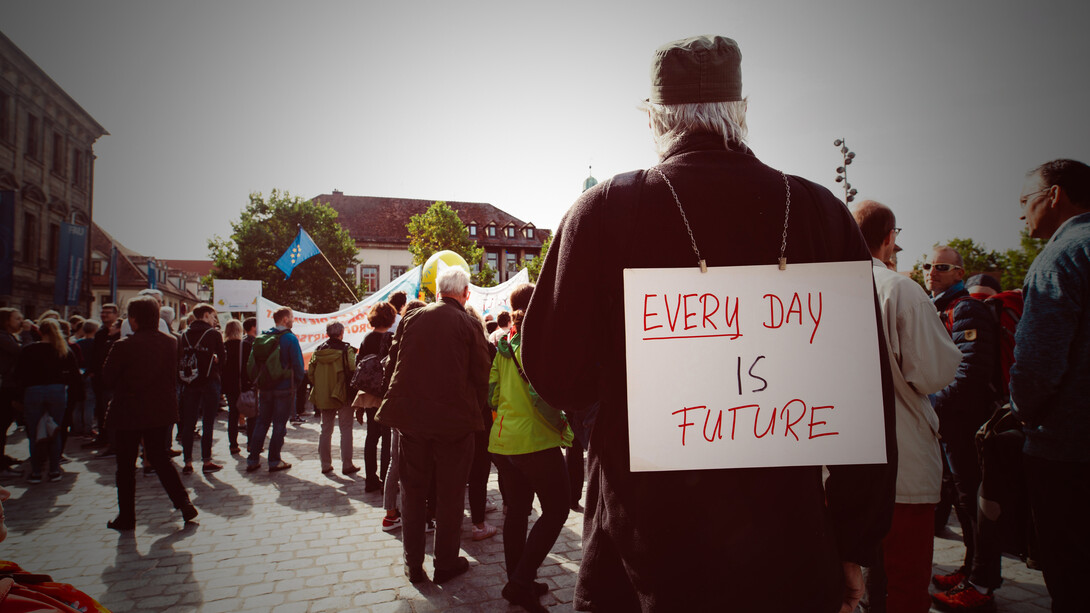 Man holding a banner reading “Every Day Is Future” during a protest