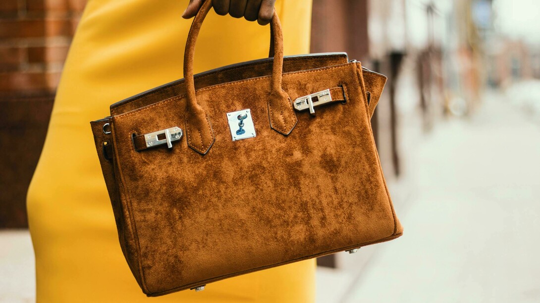 Woman carrying a brown Hermès leather tote, blending elegance with timeless design