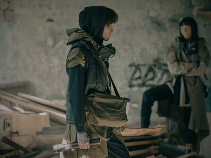 A man and a woman prepared for survival in a hostile world, highlighting perseverance born from hardship