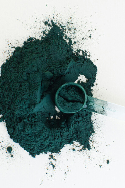 Green spirulina powder on a white table, derived from blue-green algae
