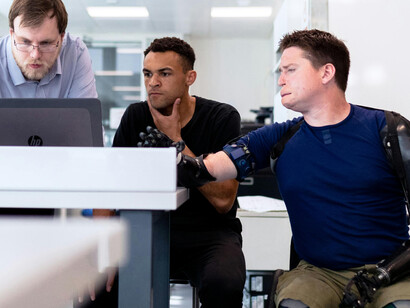 An engineer carefully fitting a prosthetic arm to enhance the mobility of a person with a disability