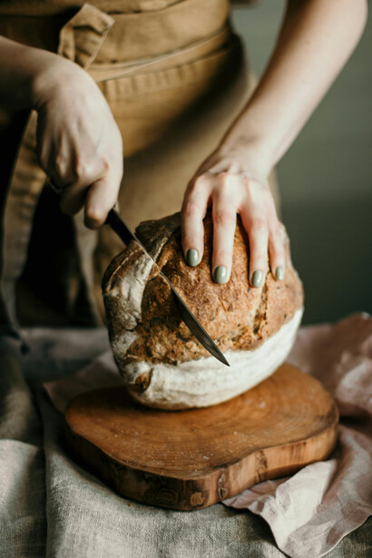 A woman places a freshly baked sourdough loaf on the table, ready to cool