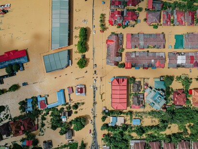 A community drowning under relentless floodwater, highlighting the vulnerability created by defective and incomplete projects