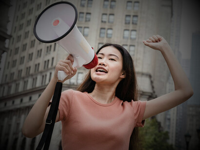 A young woman during a street protest with a megaphone, highlighting the rise of youth-driven movements shaping global politics