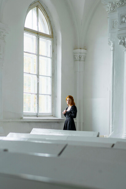 A woman in a black dress sitting alone in a quiet church