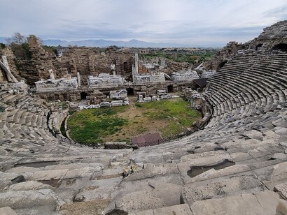 Una scena minima, quattro luci incrociate, e il miracolo si ripete: il teatro torna a respirare con chi lo guarda. Teatro romano a Side, Turchia