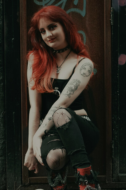 A tattooed woman with dyed hair wearing a crop top, embodying rebellious youth fashion