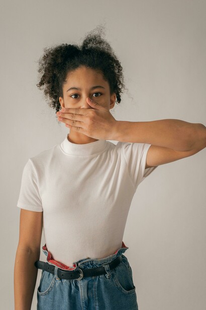 A worried Black teenage girl covering her mouth, capturing the silent anxiety and emotional turmoil many teens face in the digital age