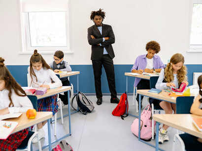 A male teacher interacts with his students in a primary school classroom