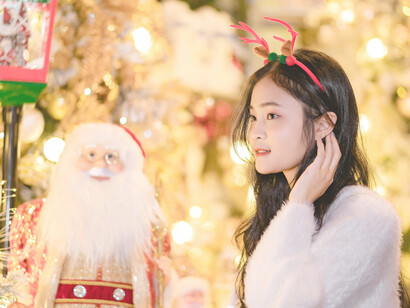 Woman with reindeer headband beside Santa figure during holiday shopping