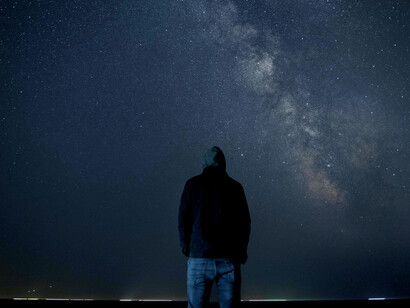 A figure looking up at the night sky, reflecting the stillness before transformation