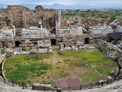 Non serve un edificio per dire chi siamo: basta un cortile, una fabbrica abbandonata, un respiro condiviso. Teatro romano a Side, Turchia
