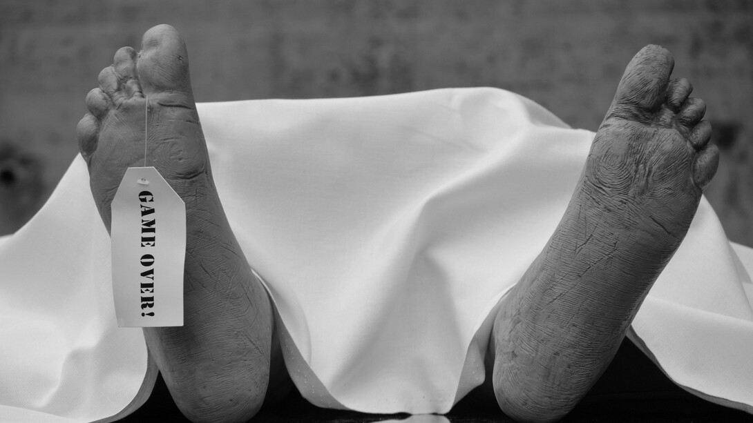 Black-and-white image of feet resting on white fabric, symbolizing a body prepared for burial on marble