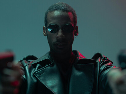 A man in a black leather jacket, armed and ready, fights to free humanity from the machines in the Matrix universe