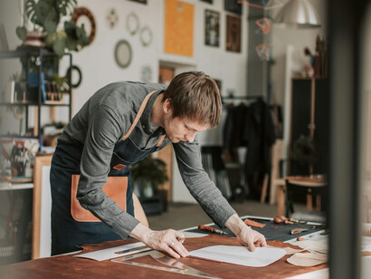 Leather craftsman at work in his atelier, surrounded by traditional leatherworking tools