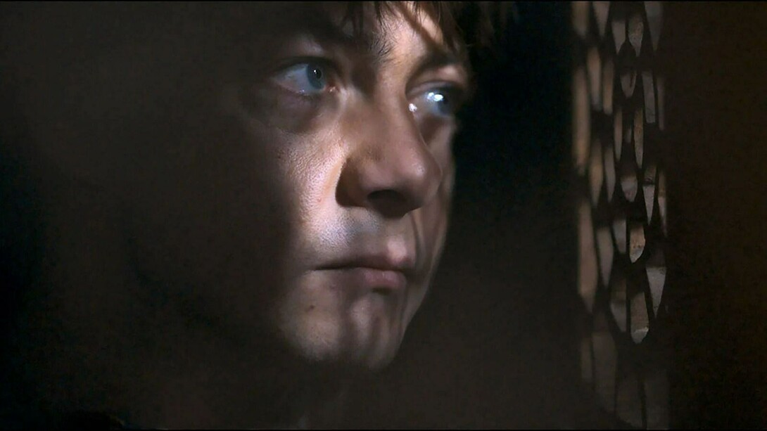 Cena do filme. A injeção de veneno em Misericórdia é construir, na figura de um padre, o contraponto libertário para tanta repressão naquela comunidade. Afinal, é o padre o único personagem que sustenta seu desejo em cena, mesmo que seu comportamento contrarie tudo o que se espera de alguém em sua posição dentro dessa engrenagem social. A inversão de papéis é explicitamente assumida na cena do confessionário, momento-chave do filme e uma das grandes cenas da filmografia de Guiraudie. A mando do próprio padre, é Jérémie quem ocupa a posição de ouvinte dentro do confessionário, enquanto, do lado de fora, o clérigo confessa o que sabe ou percebe sobre o crime e, de quebra, declara seu amor por Jérémie — que, com seu silêncio, pela primeira e única vez confessa o crime a alguém sem precisar dizer nenhuma palavra