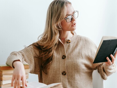 A woman in a cozy sweater and glasses reads a book at home, the perfect portrait of a true book lover
