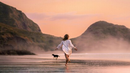Une femme qui court sur la plage avec un chien apprécie le goût de la liberté
