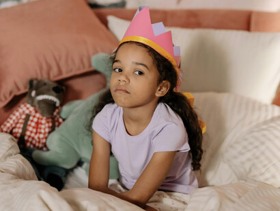 A child in a party hat looking disappointed, displaying how childhood often comes with unexpected disappointments and challenges that become festering wounds later
