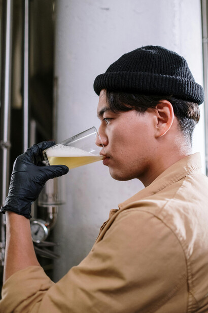 With a warm jacket and beanie, the man holds a glass of freshly brewed beer, capturing the spirit of local brewing