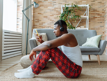 A person sits alone at home, scrolling through his phone—a quiet moment of individualism