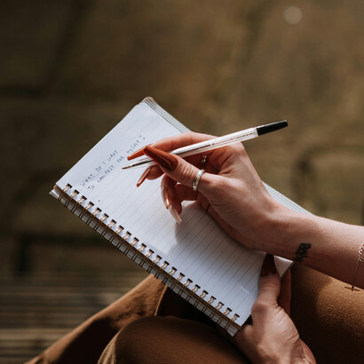 A woman in a brown blazer holds a cup of coffee, thinking quietly