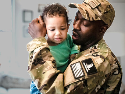 A military soldier holding his child as the family departs