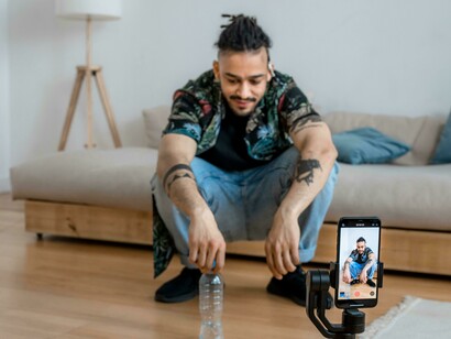 A man filming himself with a smartphone, embodying the role of a social media influencer and content creator