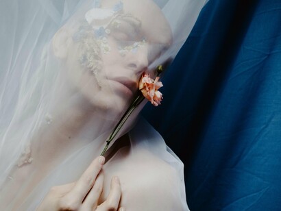 A veiled figure holding on to a flower, signifying the beauty and fragility of life