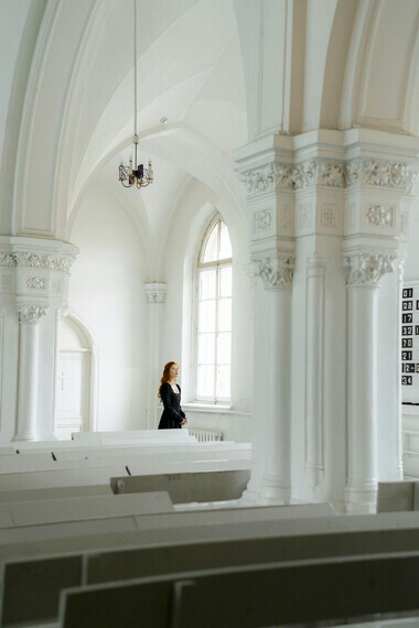 A woman in a black dress sitting alone in a church, surrounded by silence and reflection