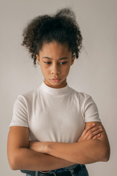 A Black teenage girl with a tense, anxious expression, reflecting the emotional impact of digital challenges and the isolation many teens experience today