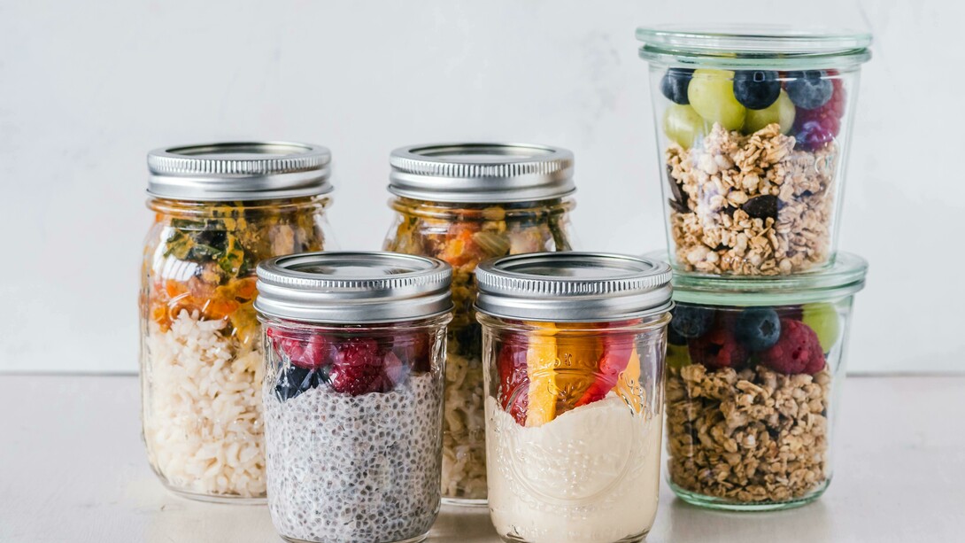 Six fruit cereal portions stored in glass mason jars, set on a white surface for easy meal prep