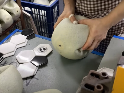 A woman is actively involved in the football manufacturing process