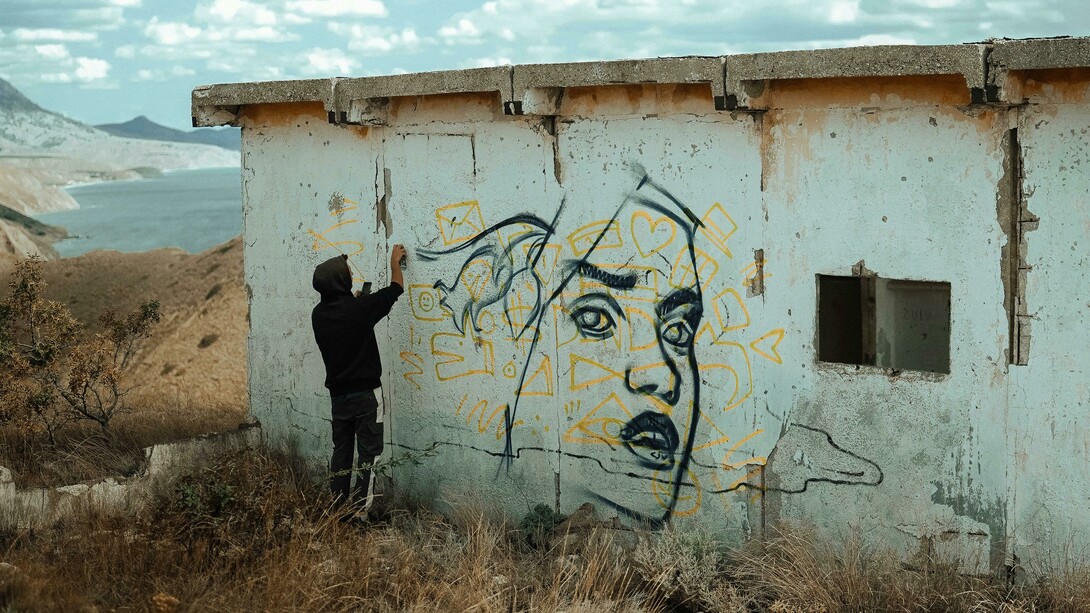 An expressive artist spray-painting the wall of an abandoned building, embodying the spirit of a creative soul