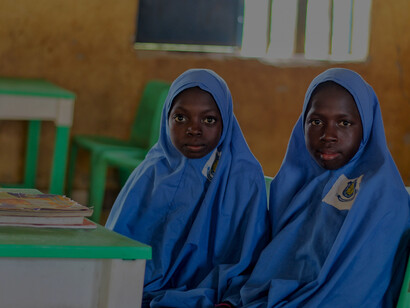 Education in rural communities: young girls wearing blue hijabs attend class, reflecting progress in gender equality and access to learning
