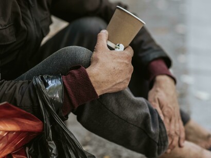 Mani e gambe di una persona che chiede l'elemosina. Chi resta ai margini, chi chiede attenzione: l'autenticità e la ricerca accurata, sia umana che documentale, sono alla base della narrazione delle storie trascurate