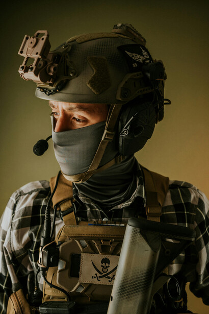 Army photo of a soldier in camouflage and helmet, armed and aiming