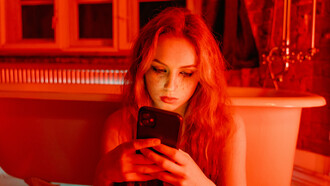 A teenager with a smudged face holding a cellphone, sitting on the bathroom floor—evoking the emotional isolation, digital dependency, and silent distress that many adolescents experience in today’s online world