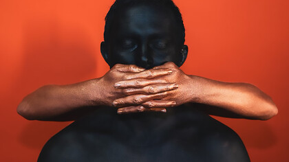 A white man covering a Black person’s face with his hands